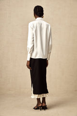 A woman wearing a colorblocked midi skirt with contrasting panels in different shades standing against a plain background
