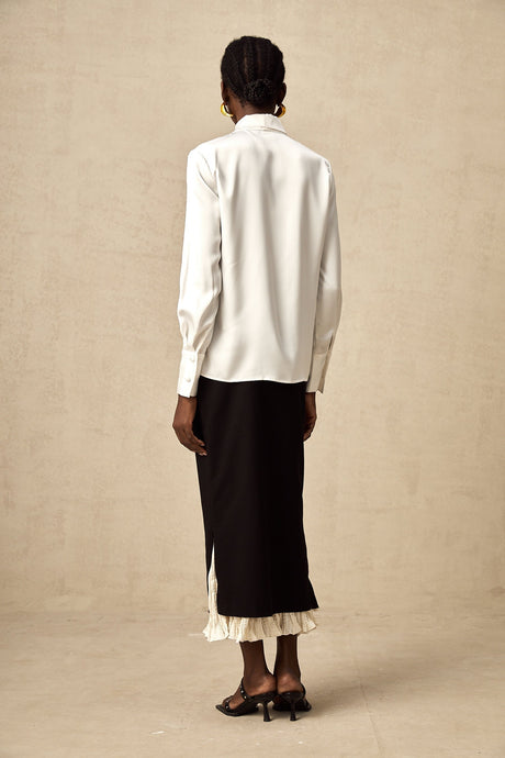A woman wearing a colorblocked midi skirt with contrasting panels in different shades standing against a plain background
