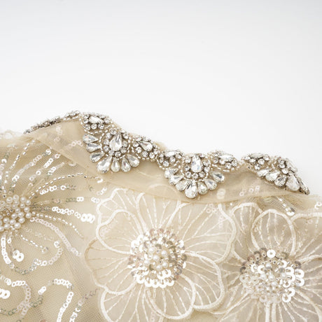 A woman wearing a delicate semi sheer jacket adorned with floral beaded patterns on organza fabric creating a light and luxurious appearance