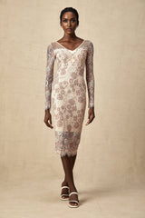 A woman wearing a fitted midi dress made of white guipure lace standing in a neutral background