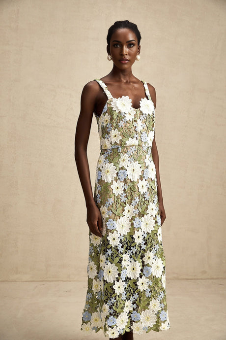 A woman wearing a floral embroidered midi dress with hollow carved details standing in a relaxed pose against a plain background