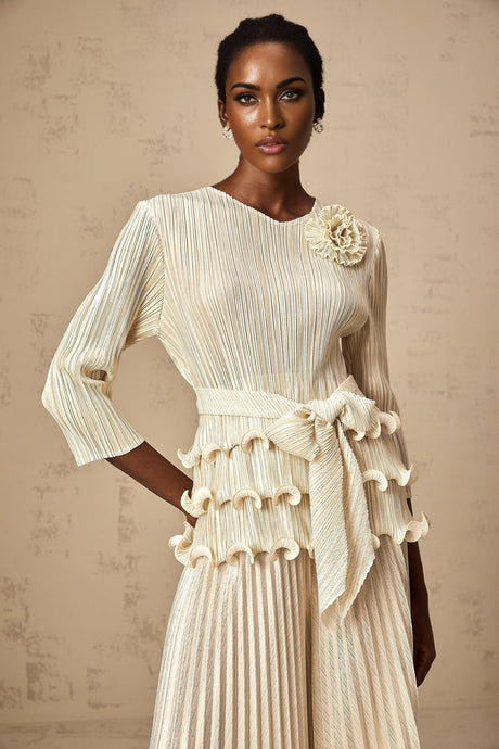 A woman wearing a floral jumpsuit with ruffles and pleats featuring applique flowers