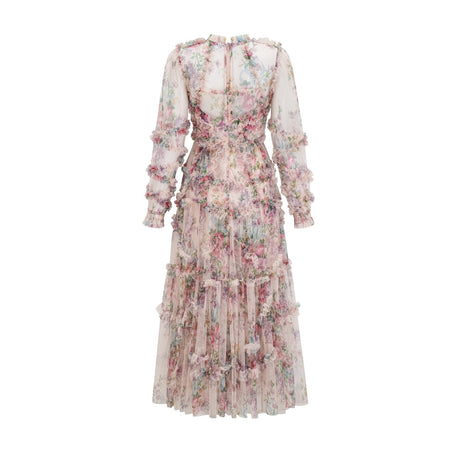 A woman wearing a floral patterned midi dress with ruffled details and a tulle skirt standing in a relaxed pose