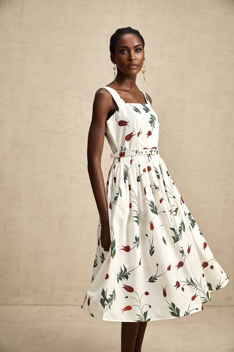A woman wearing a floral print midi dress with a light background pattern standing in a relaxed pose