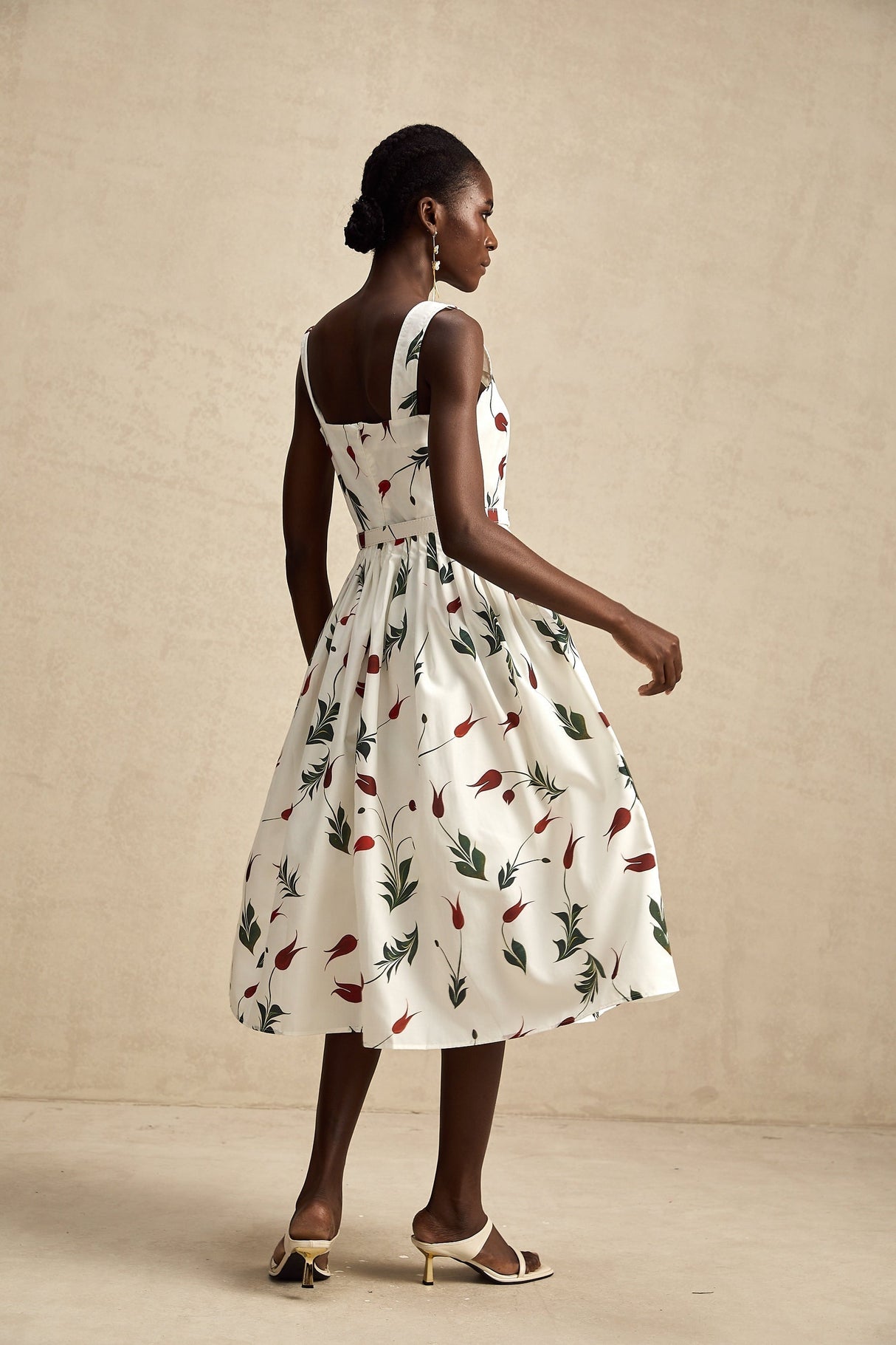 A woman wearing a floral print midi dress with a light background pattern standing in a relaxed pose