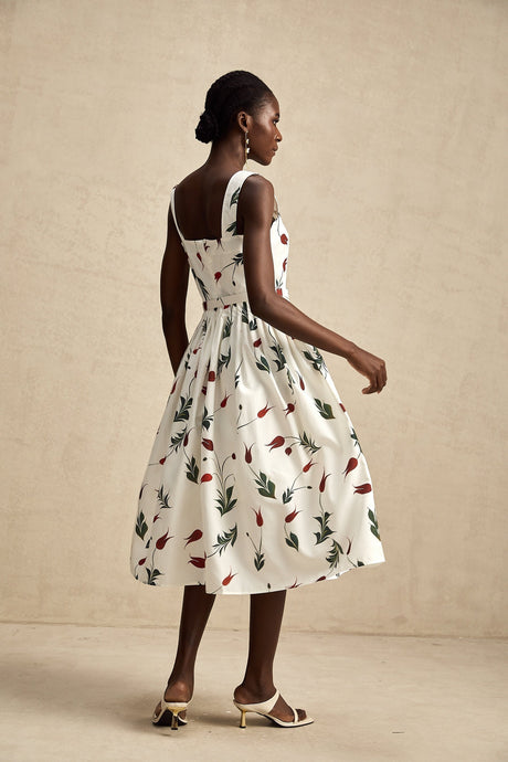 A woman wearing a floral print midi dress with a light background pattern standing in a relaxed pose
