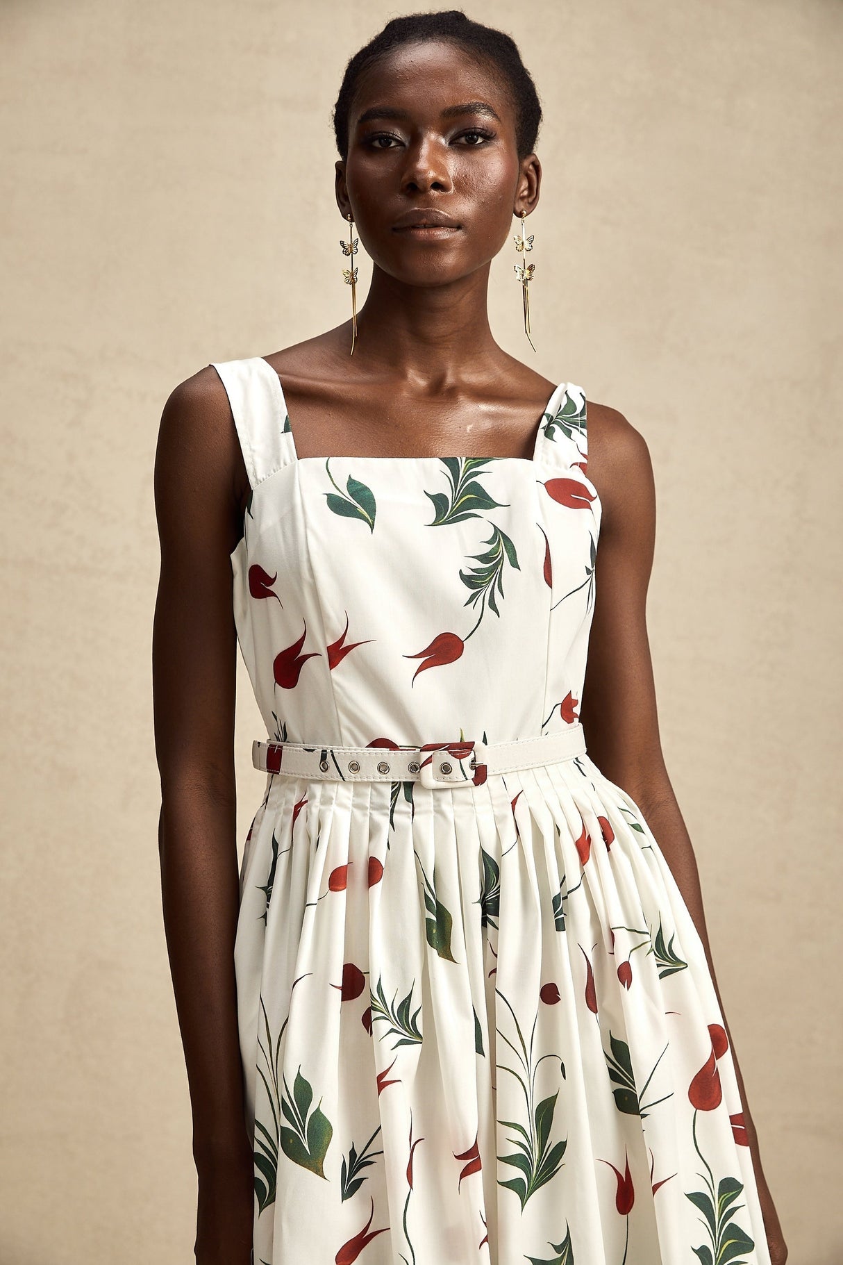 A woman wearing a floral print midi dress with a poplin fabric standing against a plain background