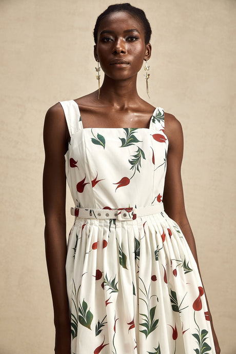 A woman wearing a floral print midi dress with a poplin fabric standing against a plain background