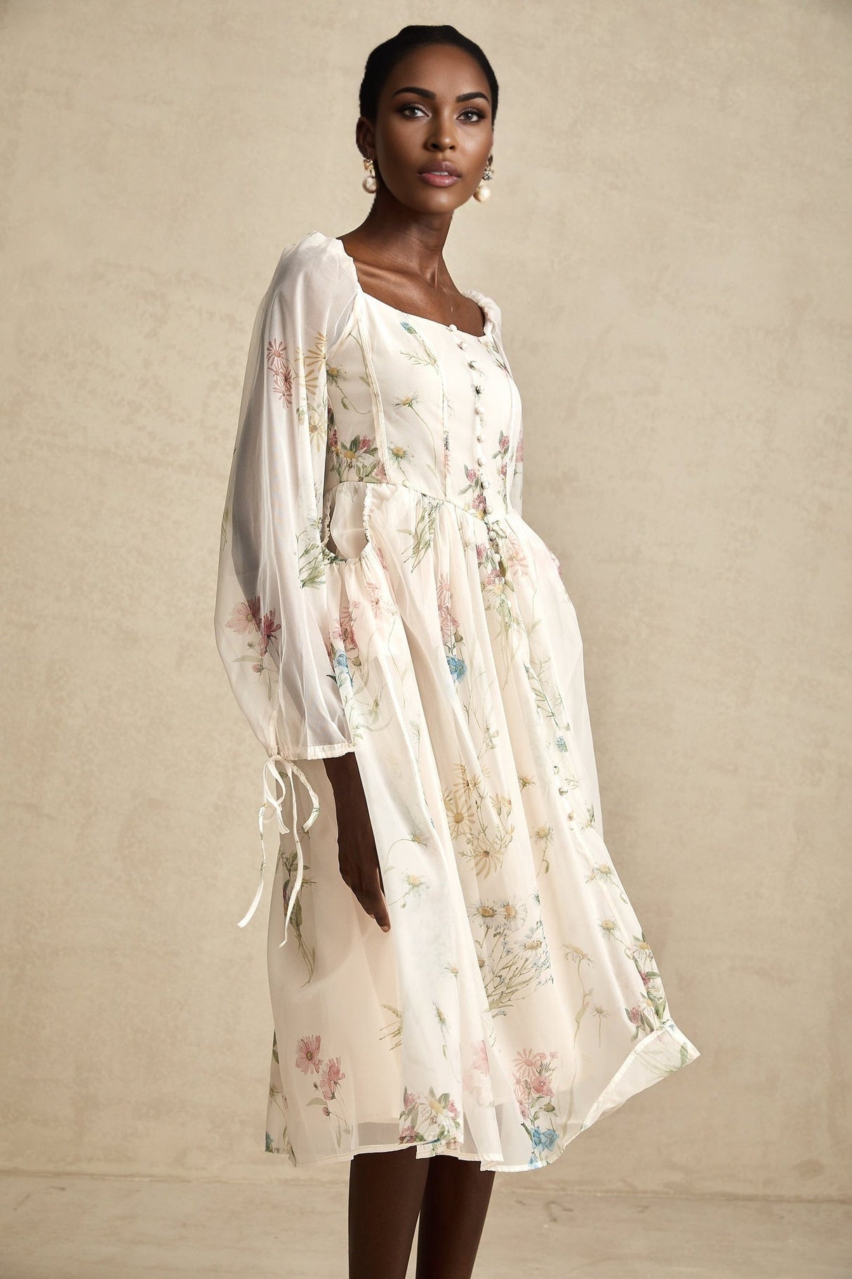 A woman wearing a floral print midi dress with a square neckline and puff sleeves against a plain background