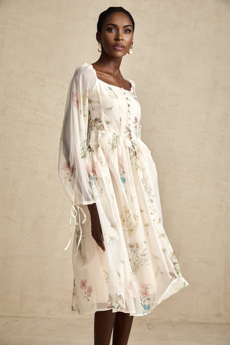 A woman wearing a floral print midi dress with a square neckline and puff sleeves against a plain background