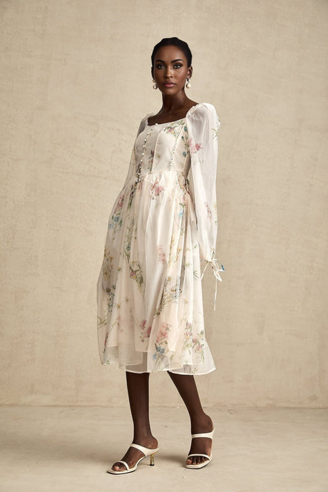 A woman wearing a floral print midi dress with a square neckline and short sleeves the dress has a fitted bodice and flowing skirt in a vibrant floral pattern
