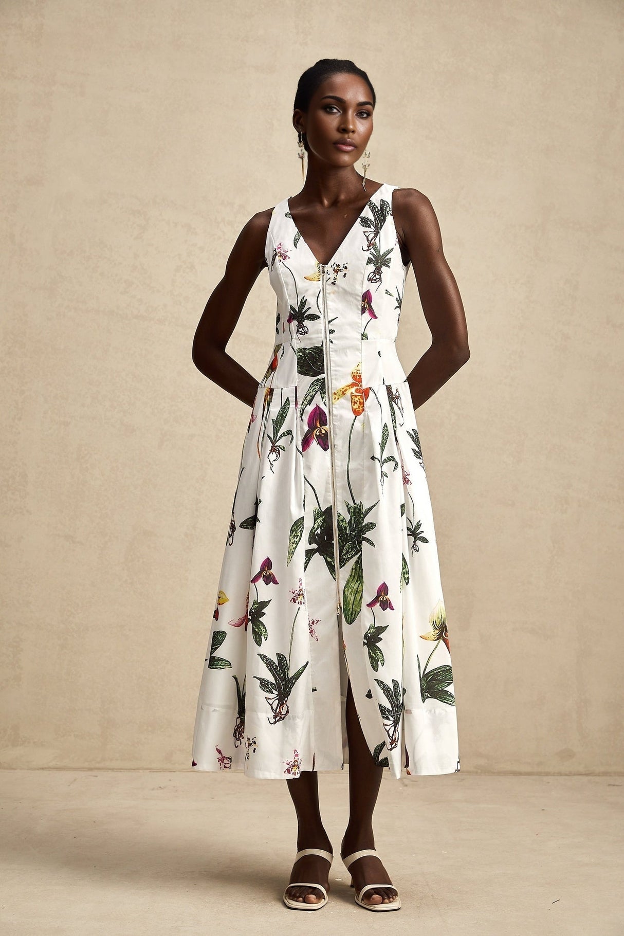 A woman wearing a floral print midi dress with a v neckline and poplin fabric The dress features a colorful floral pattern on a light background and has a fitted waist with a flowing skirt that falls to mid calf length