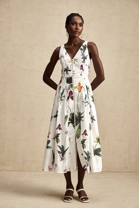 A woman wearing a floral print midi dress with a v neckline and poplin fabric The dress features a colorful floral pattern on a light background and has a fitted waist with a flowing skirt that falls to mid calf length