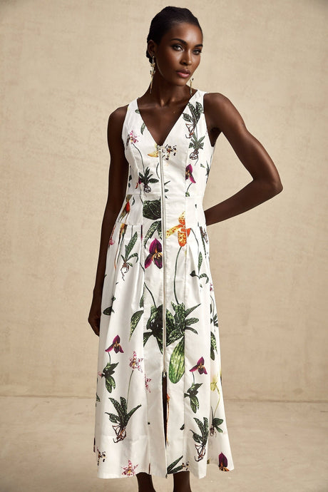 A woman wearing a floral print midi dress with a v neckline and short puff sleeves in light colored poplin fabric