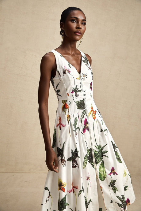 A woman wearing a floral print midi dress with a v neckline and short sleeves standing in a relaxed pose against a plain background