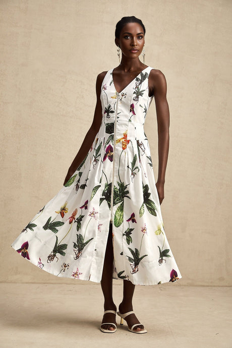 A woman wearing a floral print midi dress with a v neckline and short sleeves The dress has a light colored background with colorful flower patterns It falls to mid calf length and has a loose flowing silhouette