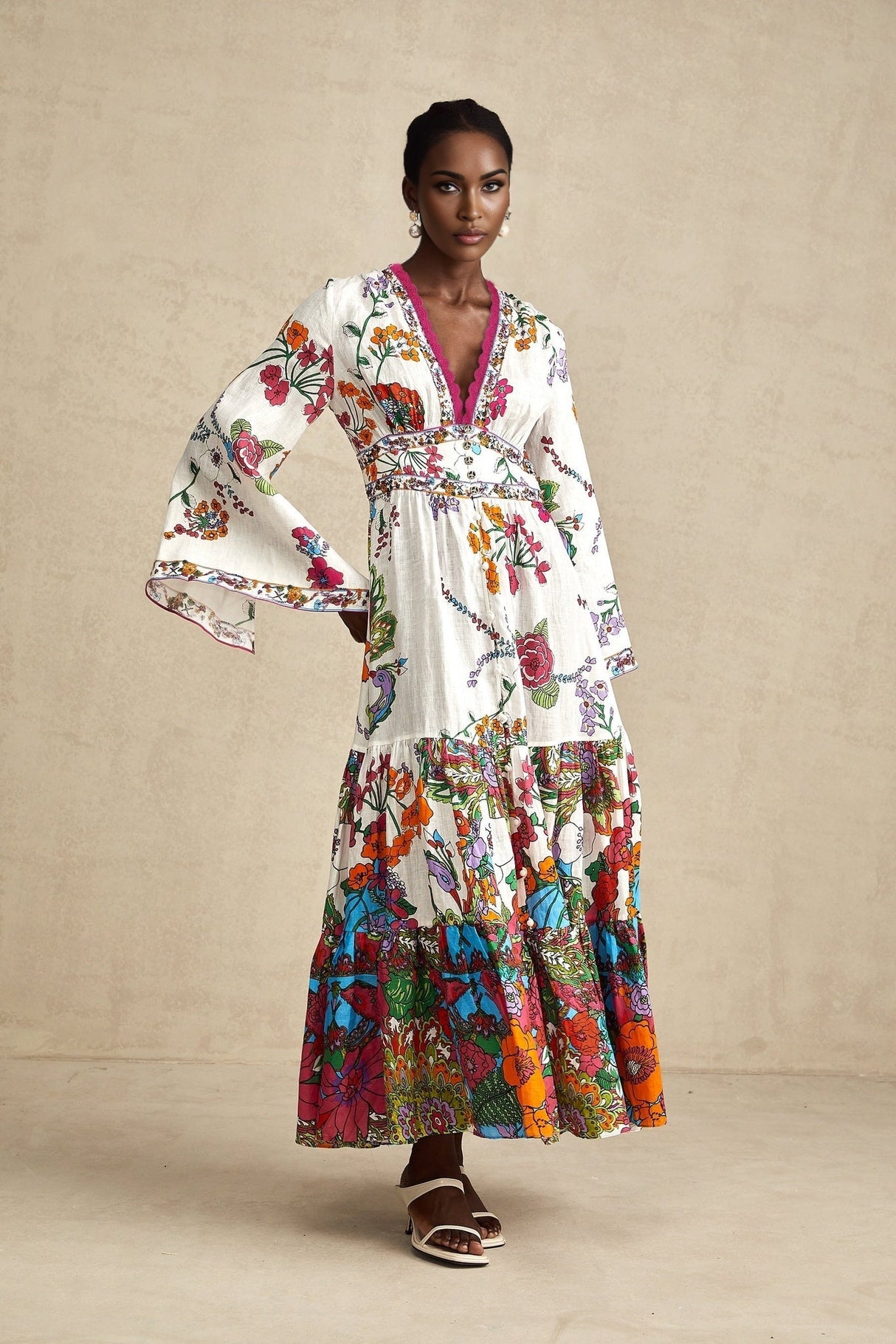 A woman wearing a floral print midi dress with a V neckline featuring a colorful pattern on a light background