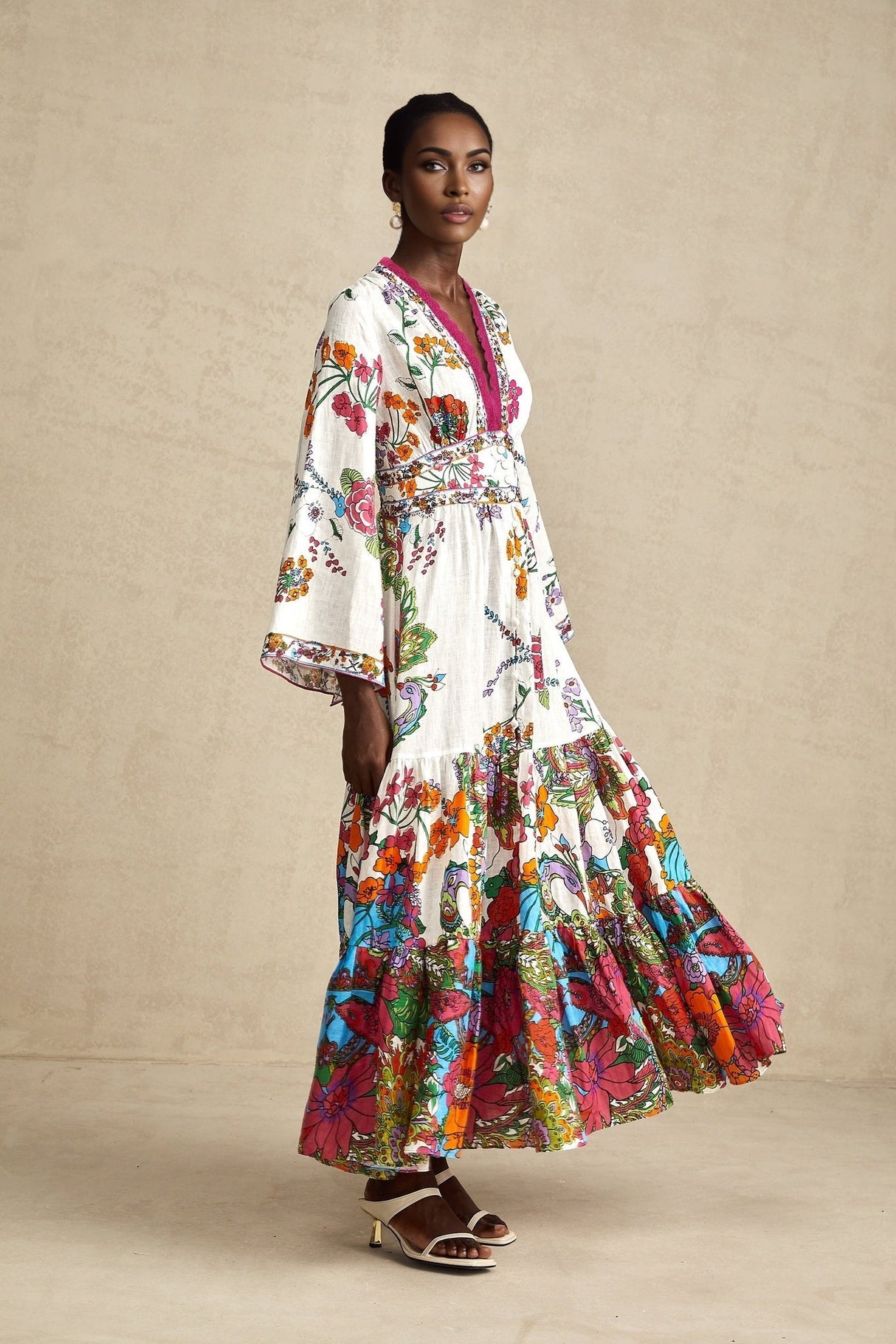 A woman wearing a floral print midi dress with a V neckline standing in a relaxed pose against a plain background
