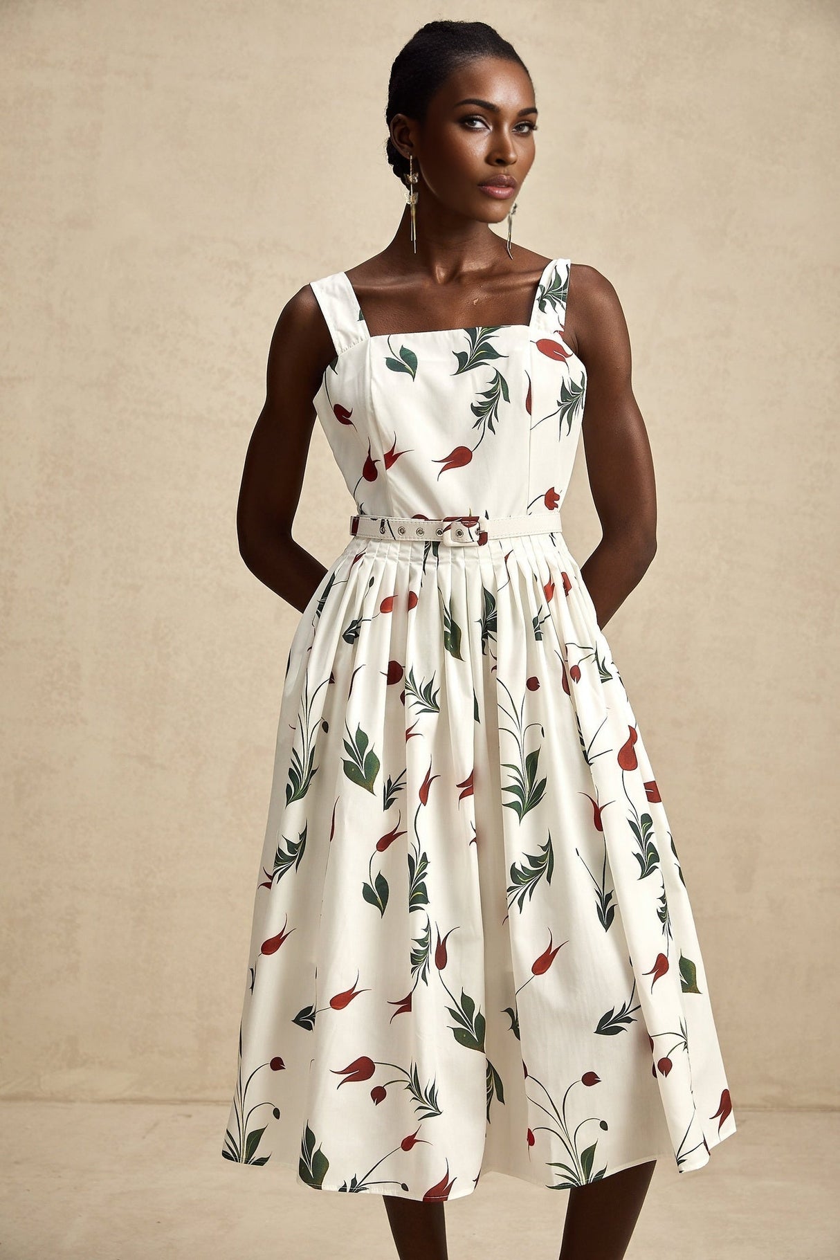 A woman wearing a floral print midi dress with a white background and colorful flower pattern standing in a relaxed pose