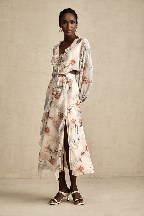 A woman wearing a floral print midi dress with an open waist design The dress features a Berengere style with a colorful floral pattern on a light background