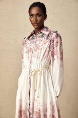 A woman wearing a floral print midi dress with lantern sleeves standing in a relaxed pose against a plain background