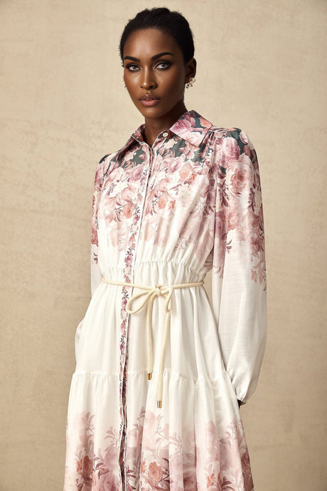 A woman wearing a floral print midi dress with lantern sleeves standing in a relaxed pose against a plain background