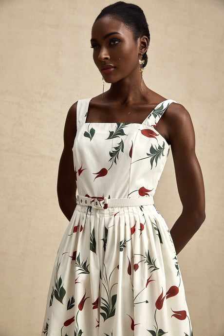 A woman wearing a floral print poplin midi dress with a white background and colorful flower pattern standing in a relaxed pose