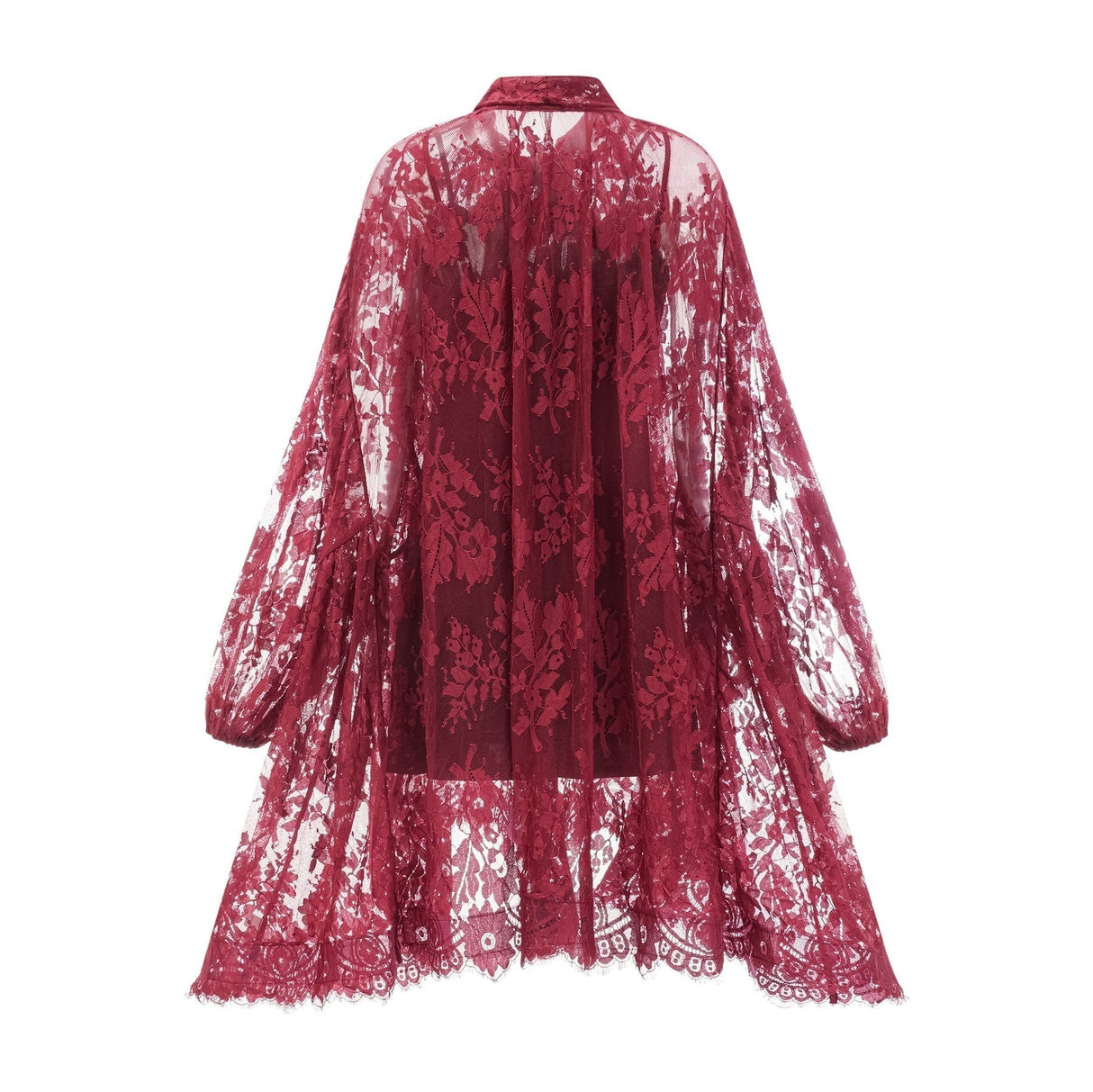 A woman wearing a flowing red lace dress with an oversized fit standing against a plain background