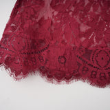 A woman wearing a flowing red oversize dress made of delicate Chantilly lace with long sleeves and a loose silhouette