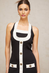 A woman wearing a formfitting knit mini dress with a halter neckline The dress features color blocking with distinct sections in different colors The model stands in a relaxed pose showing off the dresses silhouette and design