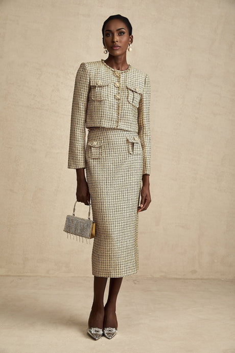 A woman wearing a gold tweed jacket and matching skirt adorned with sequins The set has a luxurious and sparkly appearance suitable for formal or festive occasions