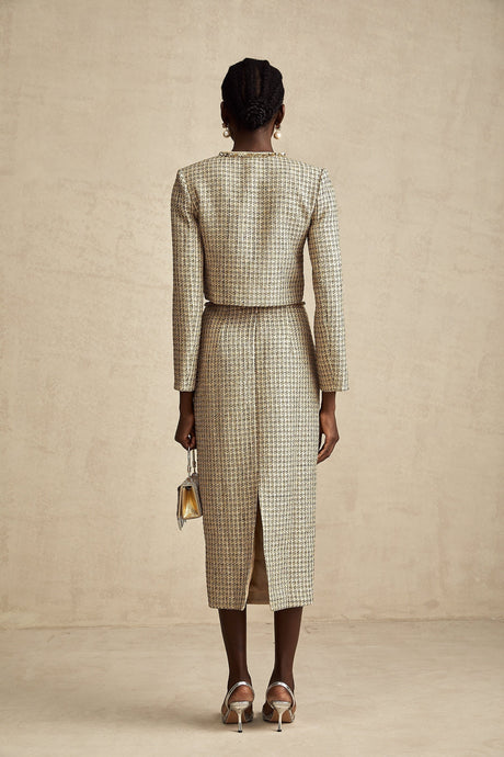 A woman wearing a gold tweed jacket and matching skirt set adorned with sequins The outfit has a luxurious and sparkling appearance suitable for formal or evening events