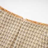 A woman wearing a gold tweed jacket and matching skirt set adorned with sequins The outfit shimmers in the light creating a luxurious and festive appearance