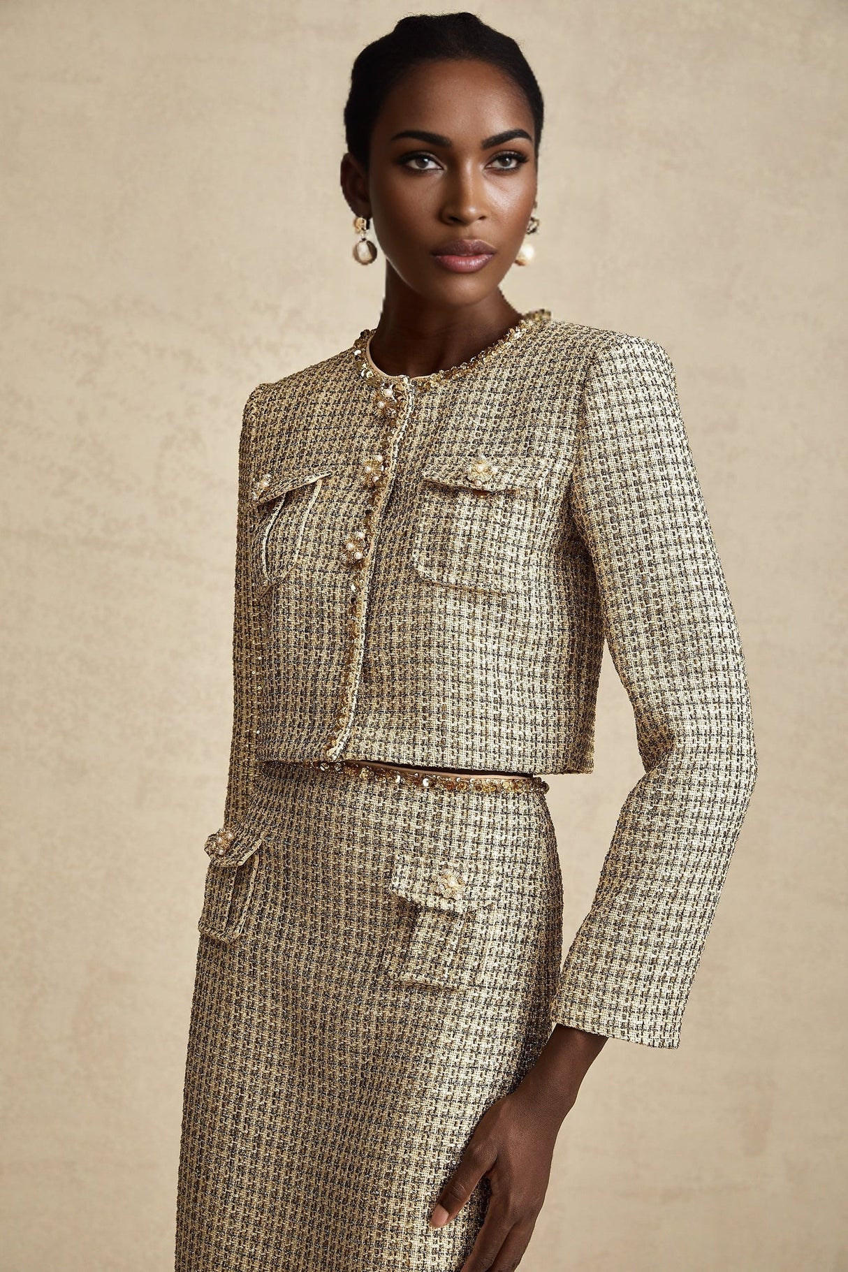 A woman wearing a gold tweed jacket and matching skirt set adorned with sequins The outfit sparkles and shimmers in the light showcasing a luxurious and festive appearance