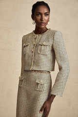 A woman wearing a gold tweed jacket and matching skirt set adorned with sequins The outfit sparkles and shimmers in the light showcasing a luxurious and festive appearance