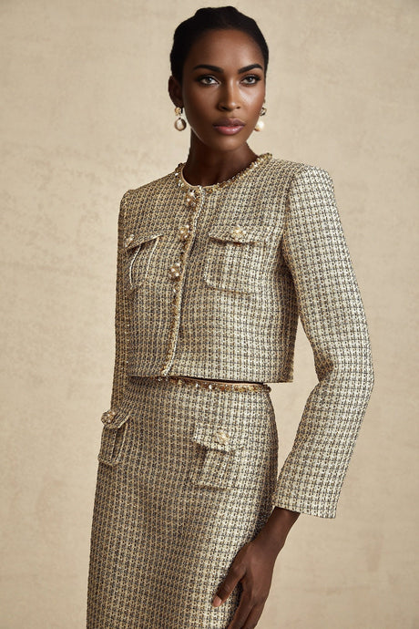 A woman wearing a gold tweed jacket and matching skirt set adorned with sequins The outfit sparkles and shimmers in the light showcasing a luxurious and festive appearance