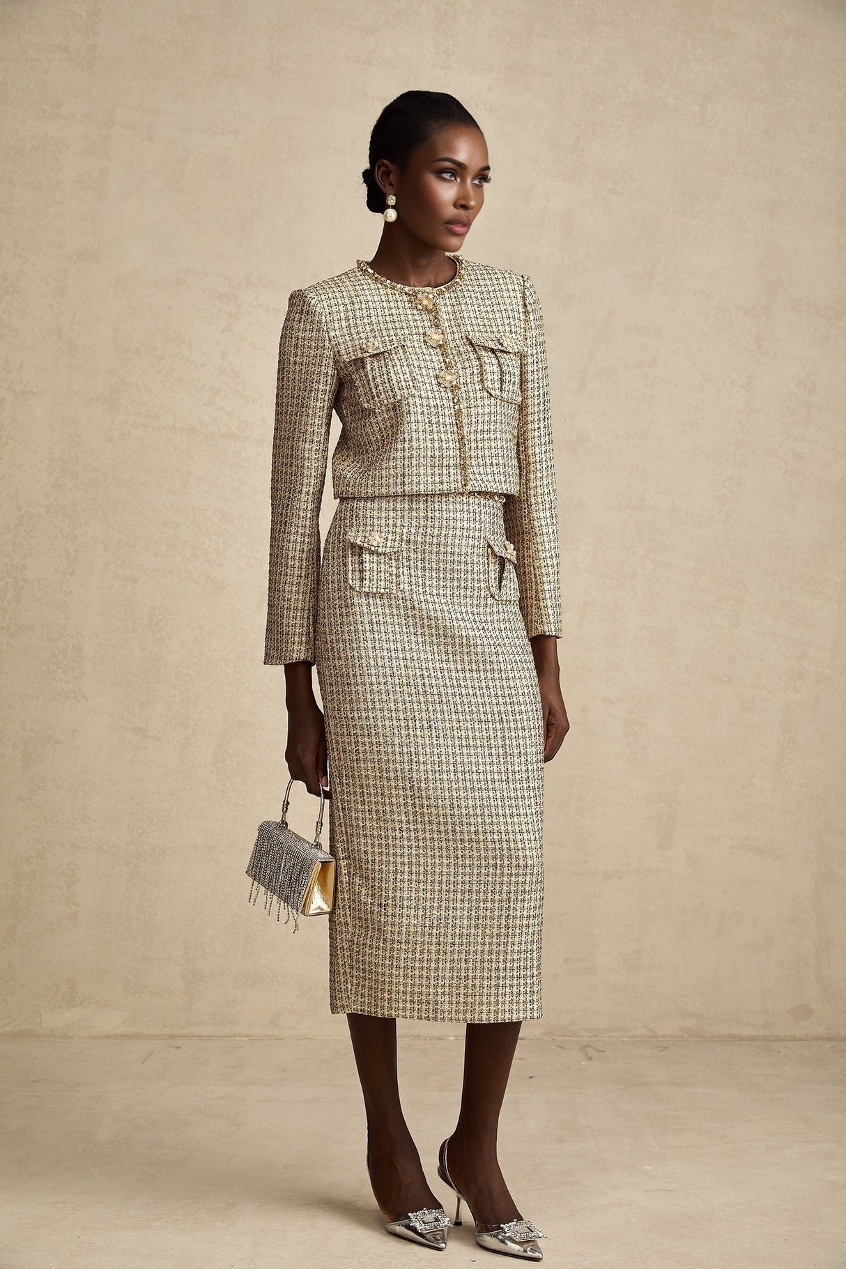 A woman wearing a gold tweed jacket and matching skirt set adorned with sequins The outfit sparkles in the light with a luxurious and festive appearance