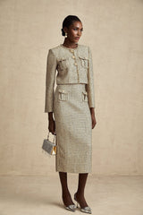 A woman wearing a gold tweed jacket and matching skirt set adorned with sequins The outfit sparkles in the light with a luxurious and festive appearance