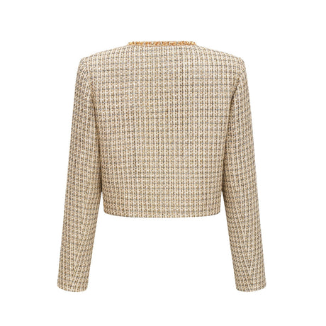 A woman wearing a gold tweed jacket and matching skirt set with sequin embellishments The outfit has a luxurious and sparkly appearance suitable for formal occasions