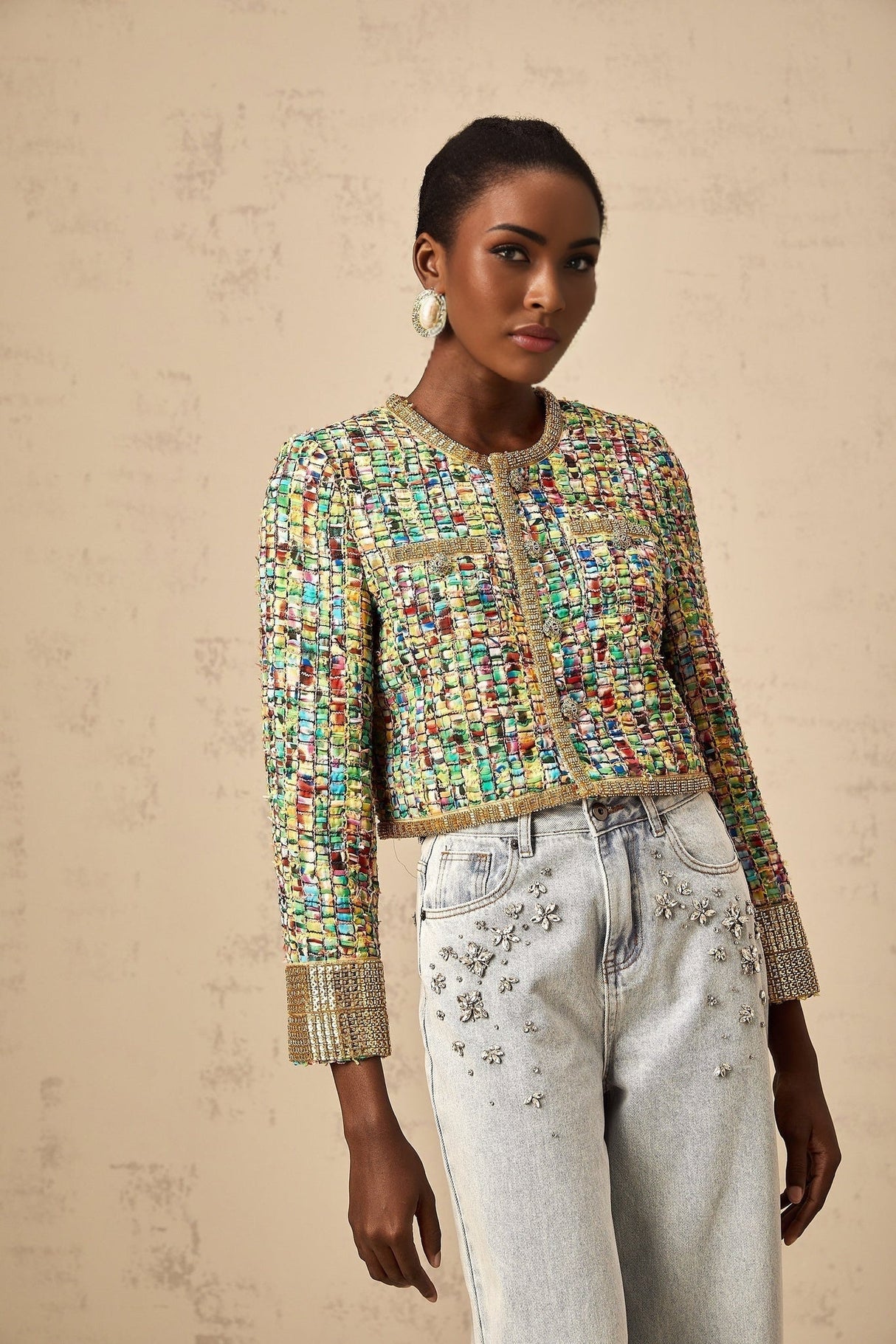 A woman wearing a gold tweed jacket with a checked pattern and sequin embellishments