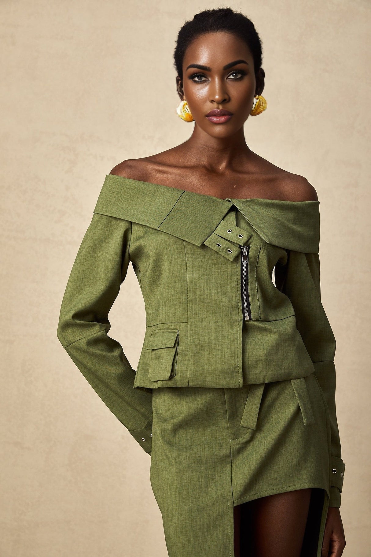 A woman wearing a green asymmetric jacket paired with a matching skirt creating a stylish two piece outfit set