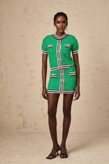 A woman wearing a green knitted matching set consisting of a top and skirt The top has long sleeves and the skirt falls to mid thigh length The set appears comfortable and stylish