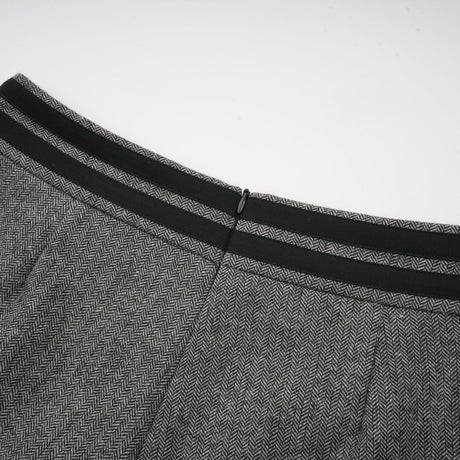A woman wearing a grey herringbone matching set consisting of a top and shorts standing against a plain background