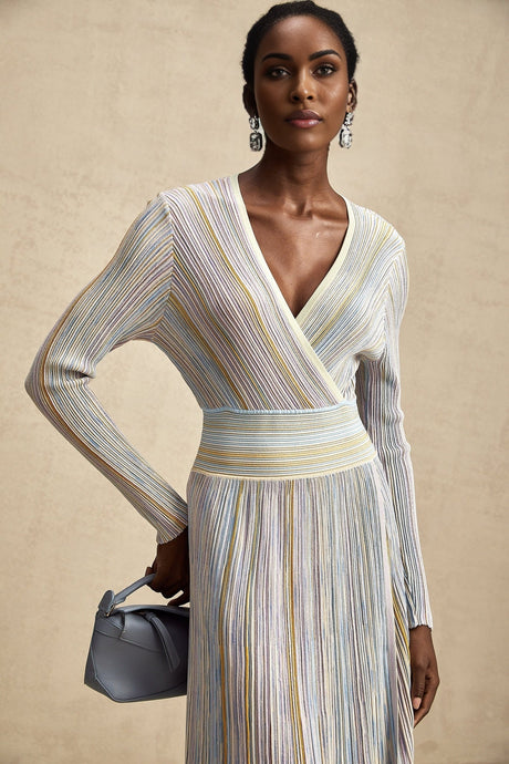 A woman wearing a kneelength knitted dress with vertical stripes named Amelie The dress has a fitted silhouette and alternating colored stripes running from top to bottom