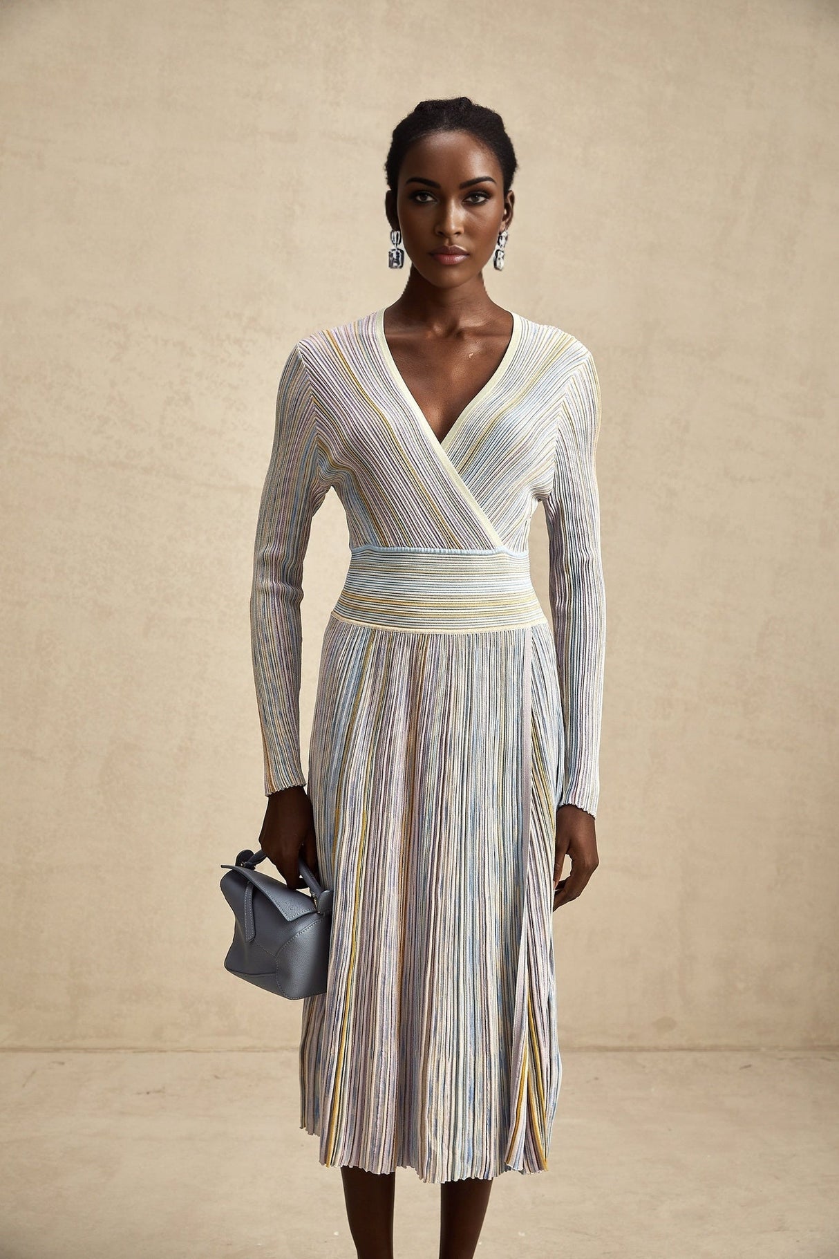 A woman wearing a kneelength knitted dress with vertical stripes standing in a relaxed pose the dress has a fitted silhouette and long sleeves showcasing the Amelie design