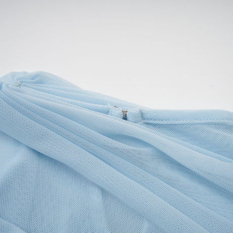A woman wearing a light blue asymmetric pleated maxi dress with a flowing skirt and one shoulder design