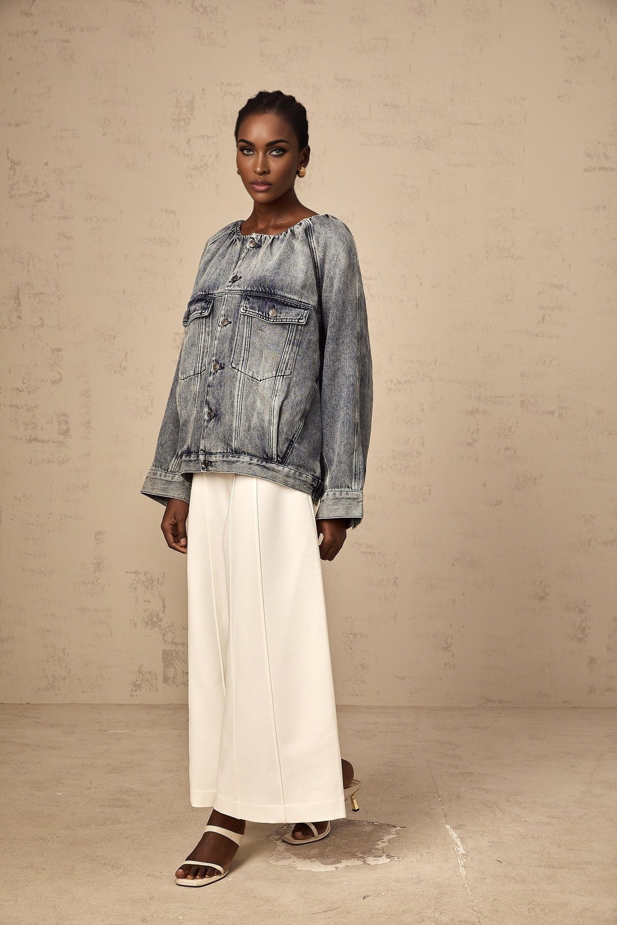 A woman wearing a light blue collarless denim jacket with long sleeves and buttoned front