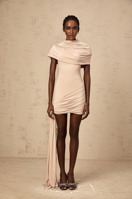 A woman wearing a lightcolored fitted mini dress with capelike sleeves and ruched detailing