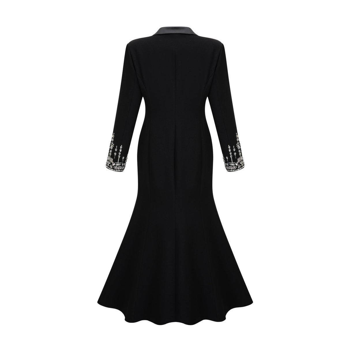 A woman wearing a long black blazer dress with embellishments standing in a relaxed pose against a plain background