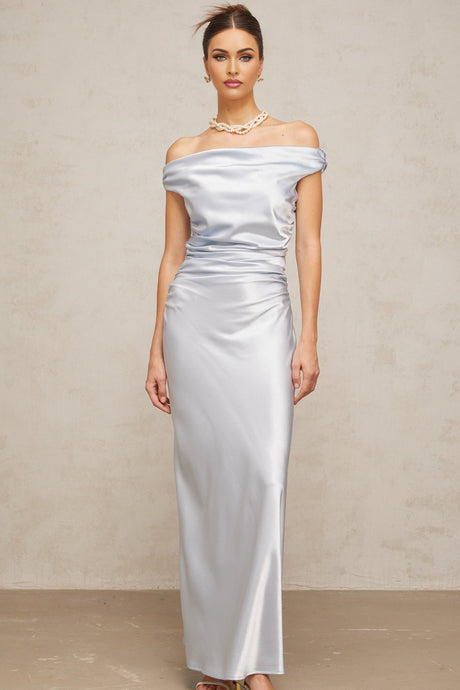 A woman wearing a long blue satin dress with offshoulder sleeves and ruched detailing standing in an elegant pose